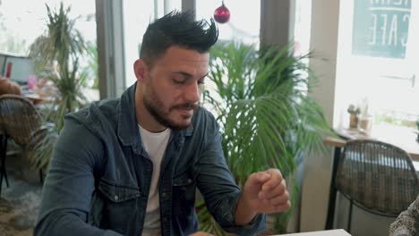 bearded man drinking coffee and talking with friend in cafe