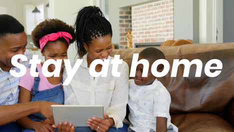 animation of stay at home text over parents with son and daughter using tablet at home