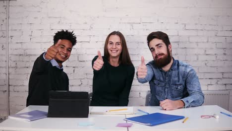 Ein-Multiethnisches-Geschäftsteam-Zeigt-Den-Daumen-Nach-Oben,-Während-Es-Am-Tisch-Im-Modernen-Büro-Sitzt.-Zeitlupenaufnahme