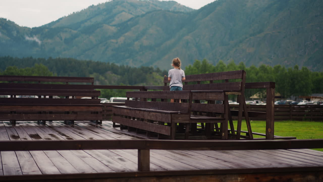 작은 소녀 가  ⁇ 은 나무 벤치 를 따라 춤 을 추고 있다
