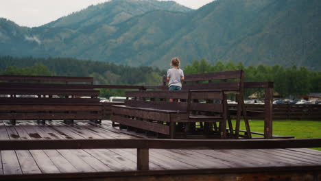 Little-girl-walks-along-wet-wooden-benches-on-dancing-ground