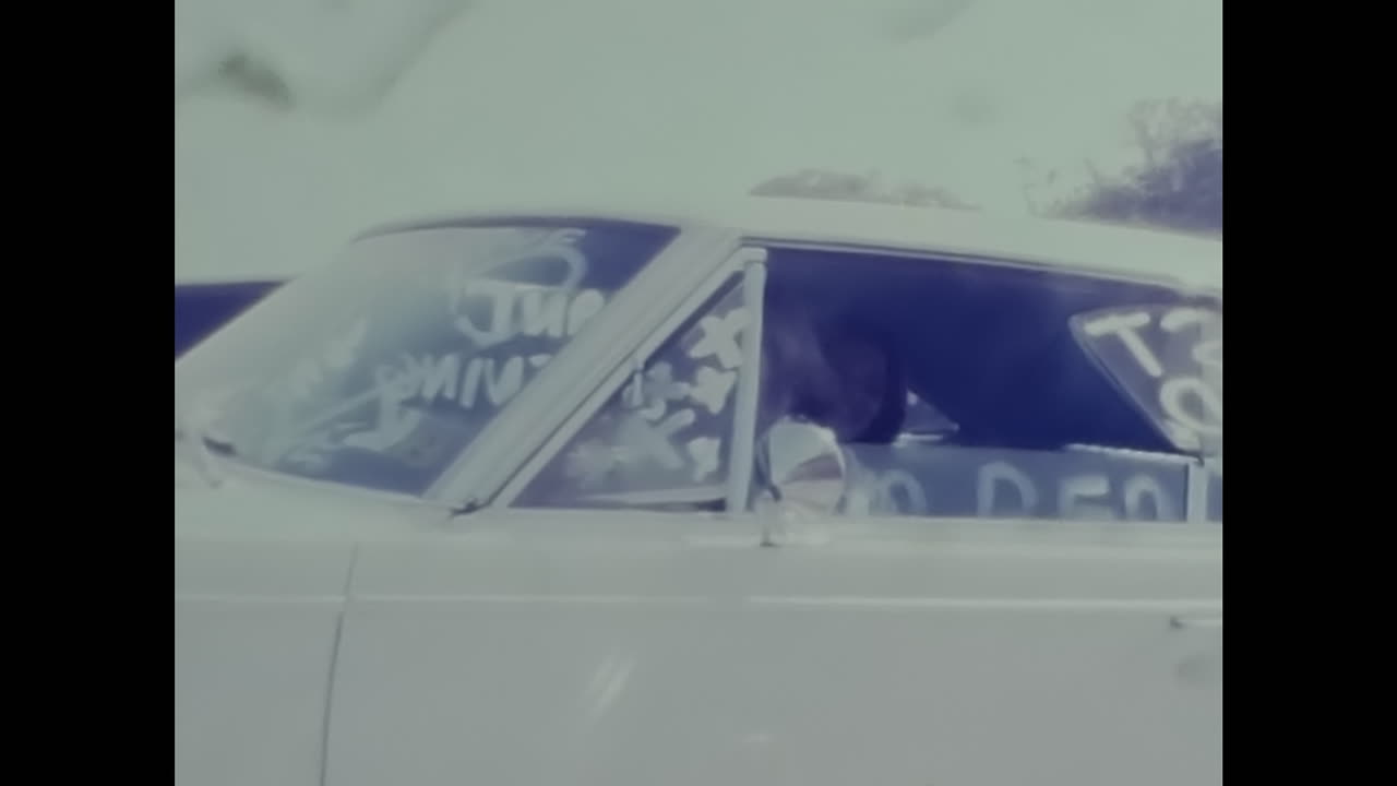 Vintage Car Driving Past Traffic Light on American Street in 1970s. CIRCA USA - 1970s: A vintage car can be seen driving down a street in 1970s America next to a classic traffic light.