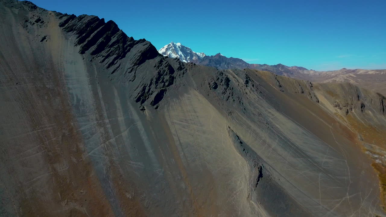 Aerial view flying over a dark rocky ridge in the highlands of the Andes mountain range.