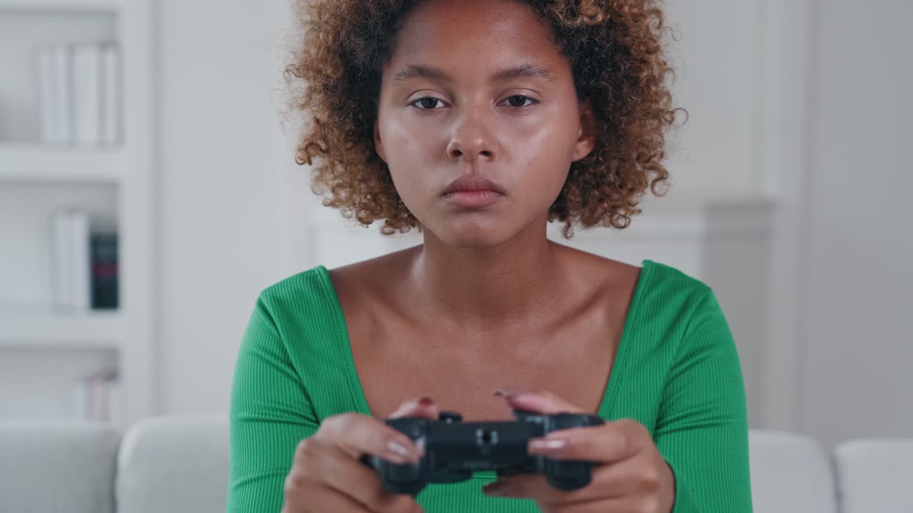 giovane donna afroamericana adolescente tiene il joystick per i videogiochi si siede sul divano