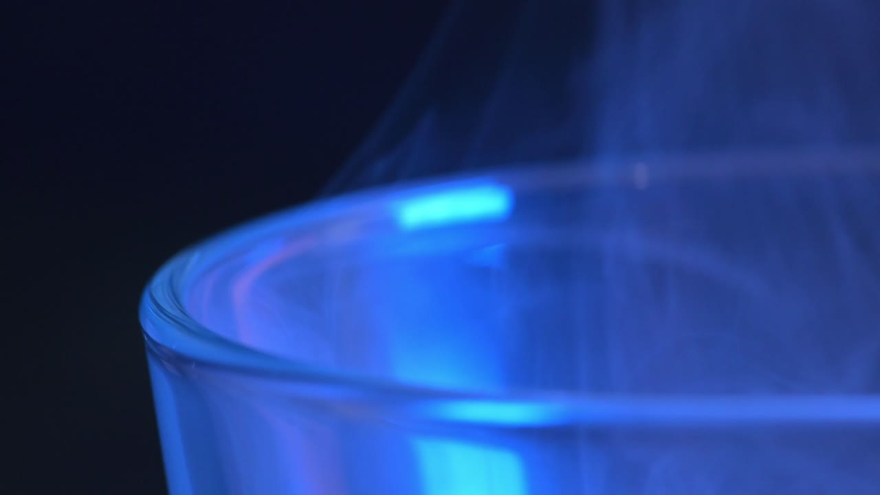 맥로: 파란색 연기가 흐르고 상승하는 유리잔의 가장자리