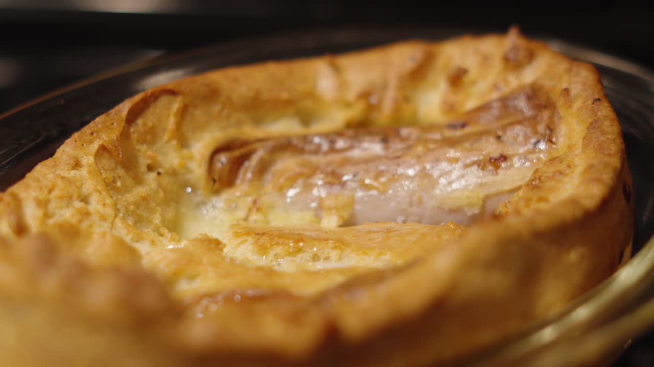 Nærbilde av nylaget «toad in the hole» med Yorkshire pudding-røre og pølser. Matlaging klar til servering. Tradisjonelt klassisk britisk vintermåltid