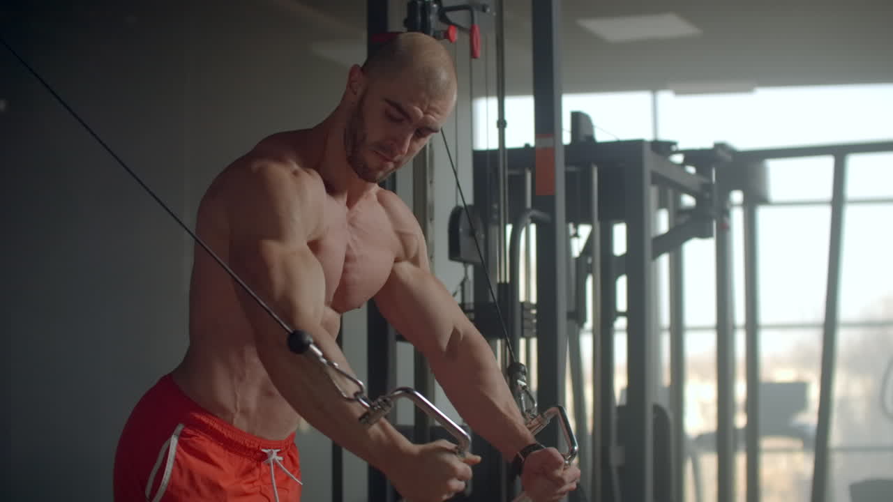 brutal guapo culturista caucásico trabajando en el gimnasio pecho de entrenamiento bombeando los músculos pectorales con pesas y en cruces ganando peso y poses concepto de fitness y culturismo