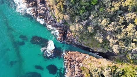 Breathtaking-Aerial-View-of-a-Pristine-Turquoise-Cove-Surrounded-by-Rugged-Coastal-Terrain-and-Lush-Greenery