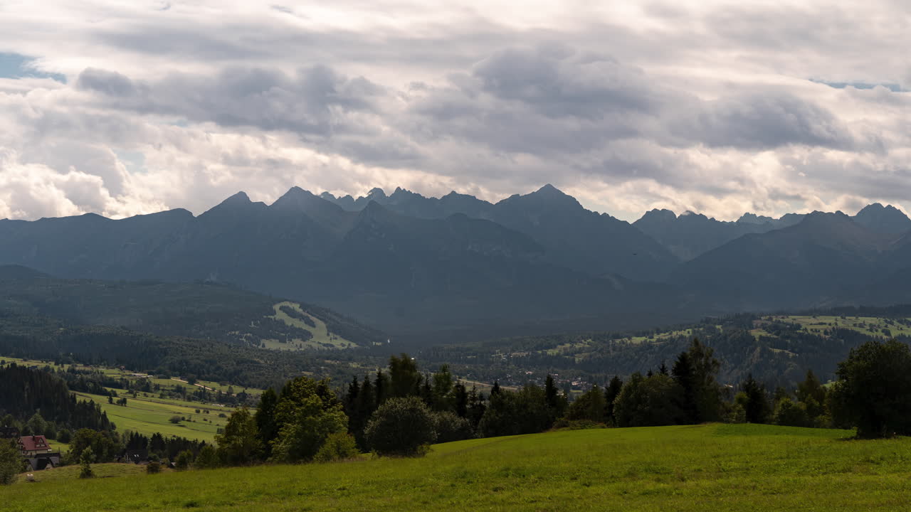 Timelapse che mostra nuvole che si muovono sulle montagne Tatra e un prato sullo sfondo