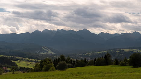 Timelapse-showing-clouds-moving-over-the-Tatra-mountains-and-a-meadow-in-the-background