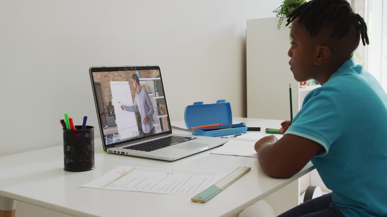 African american boy having a video call on laptop while doing homework at home