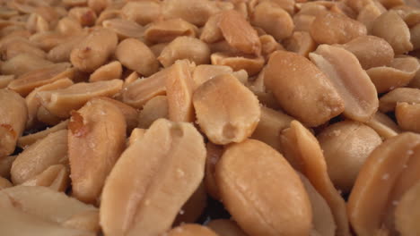 salted toasted peanuts turning macro view, food product used in many commercial producers and recipes like chocolates, sauces and oils, known allergen, healthy nuts, peanut allergy, 4k shot