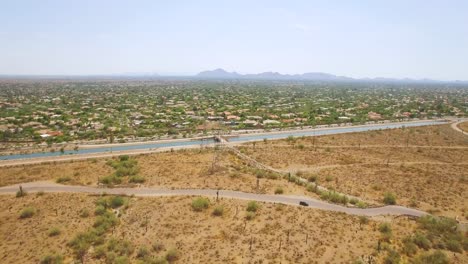 Aerial-slow-pull-back-from-the-Hayden-Rhodes-Aqueduct-canal-cutting-across-the-Sonoran-desert-near-Taliesin-West,-Scottsdale,-Arizona