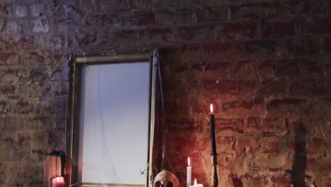 video de una pila de libros, marco con tela de araña, cráneo y velas en el fondo de la pared de ladrillo