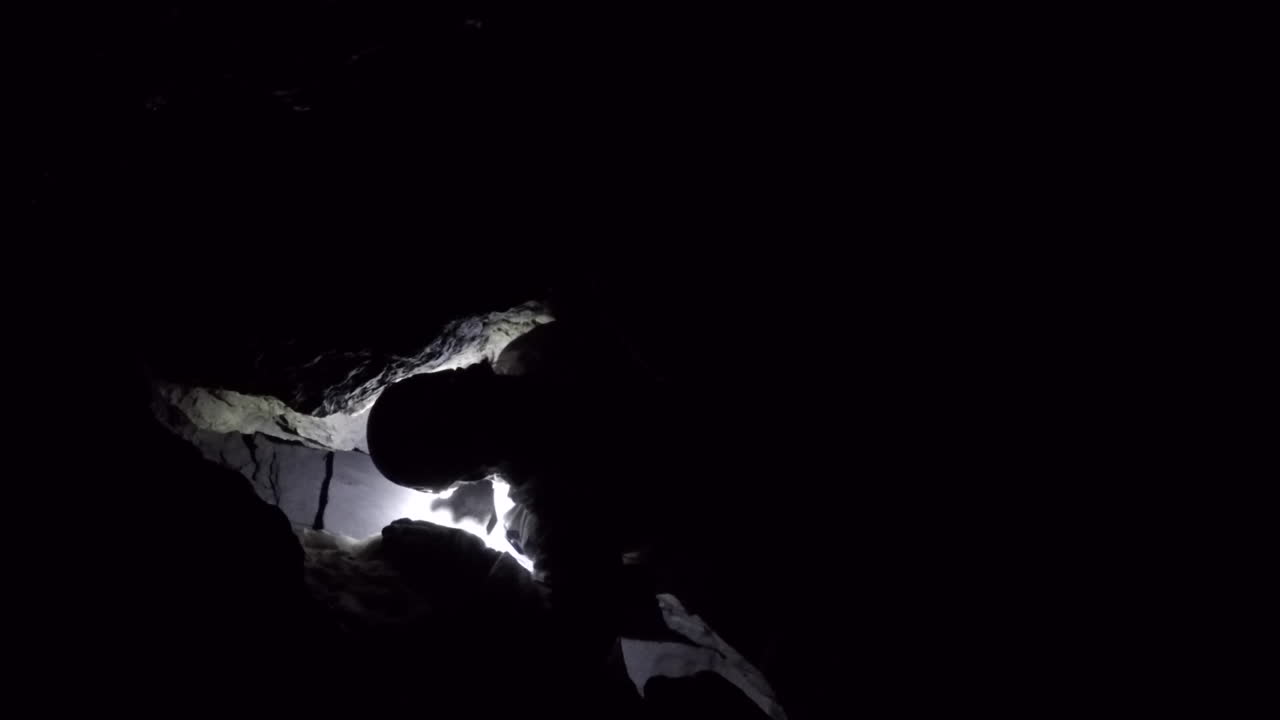 Cave spelunker descends into deeper passage through a restriction