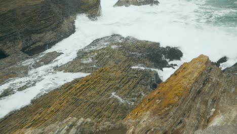 Olas-En-Cámara-Lenta-Rompiendo-Sobre-Acantilados-Costeros-En-Un-Día-Nublado-De-Verano