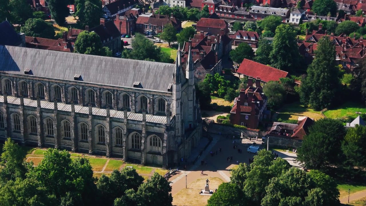 Detaljerede droneoptagelser, der passerer Winchester Cathedral, dens område og omkringliggende historiske hustage i Hampshire, England. Forhøjet udsigt, der fremhæver middelalderlig gotisk arkitektur.