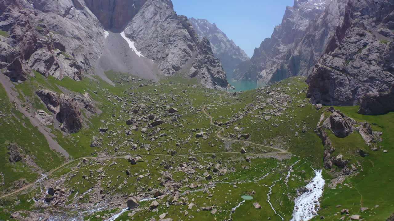 impresionante vista aérea sobrevolando un valle de montaña para revelar el majestuoso lago alpino kel suu, kirguistán