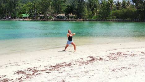 Blonde-attractive-caucasian-woman-relaxing-on-the-sandy-beach-practicing-yoga-on-summer-vacation