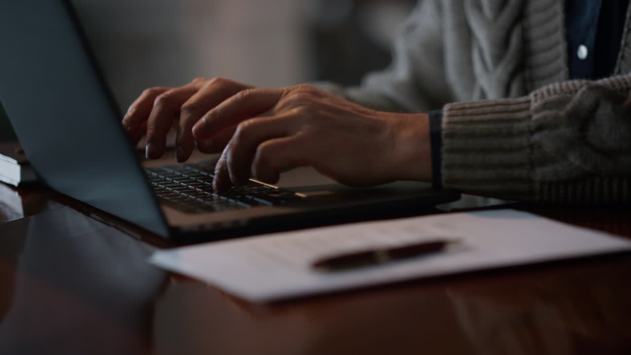 Closeup old man hands typing on computer at home