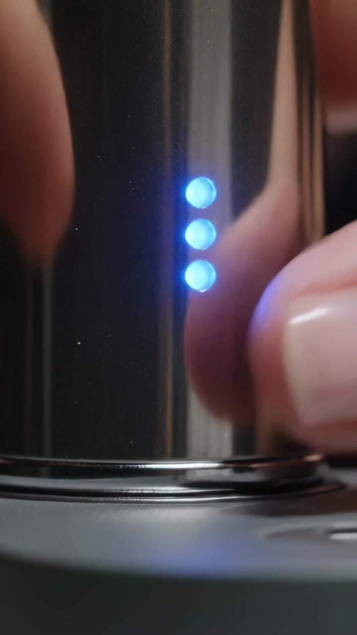 Vertical video: Placing fingers lining cap above rim on metal cylinder on table, powering blue LEDs