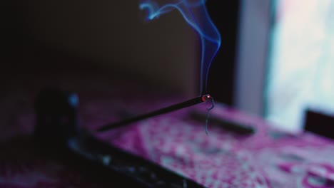 dancing smoke from burning incense stick in holder on table indoor