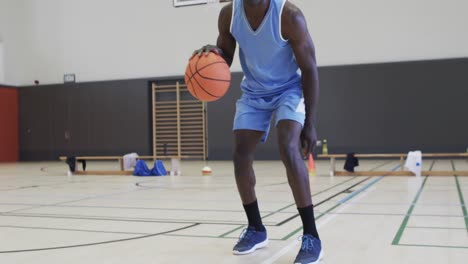 portrait of african american male basketball player playing in indoor court, in slow motion