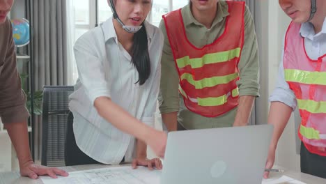three asian engineers with helmets using laptop for working to a man at the office