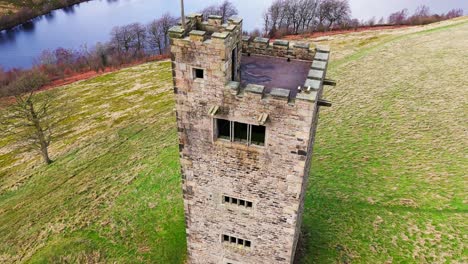 old derelict castle, monument, disused stone tower, with people walking around and flying a drone