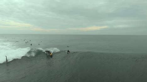 aerial shot of pro surfer riding big wave on a yellow board on a cloudy day in pichilemu, chile-4k