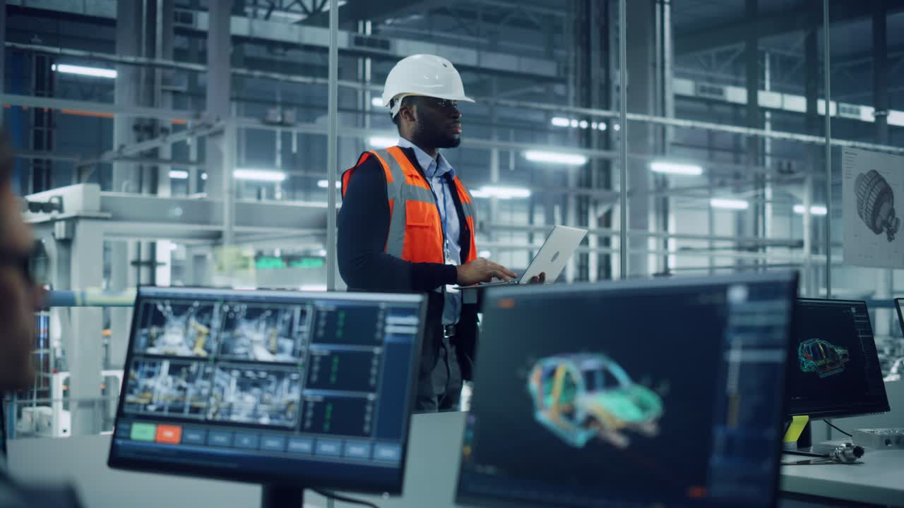 African American Engineer Using Laptop Computer and Looking Out of the Office at a Car Assembly Plant. Vehicle Factory Line Operator Working at Desk, Overviewing Autonomous Electric Car Production.