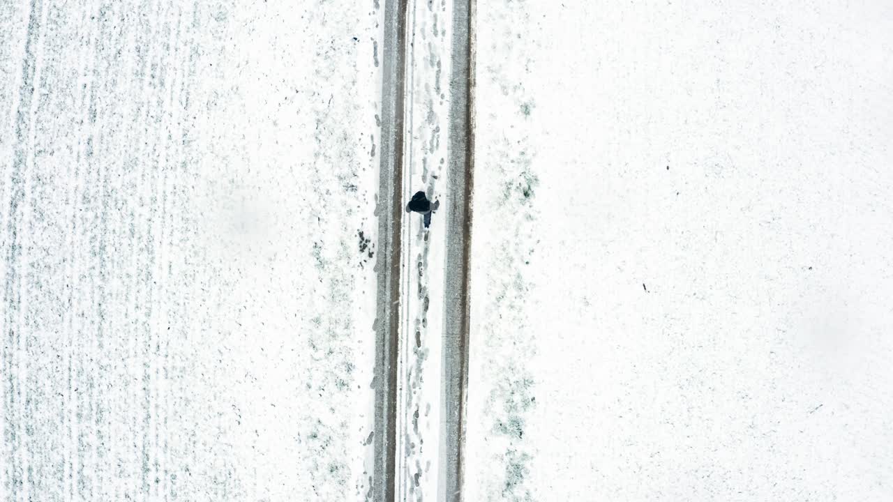 눈보라 속에서 눈 덮인 길을 걷고 있는 남자의 최고 정적 샷