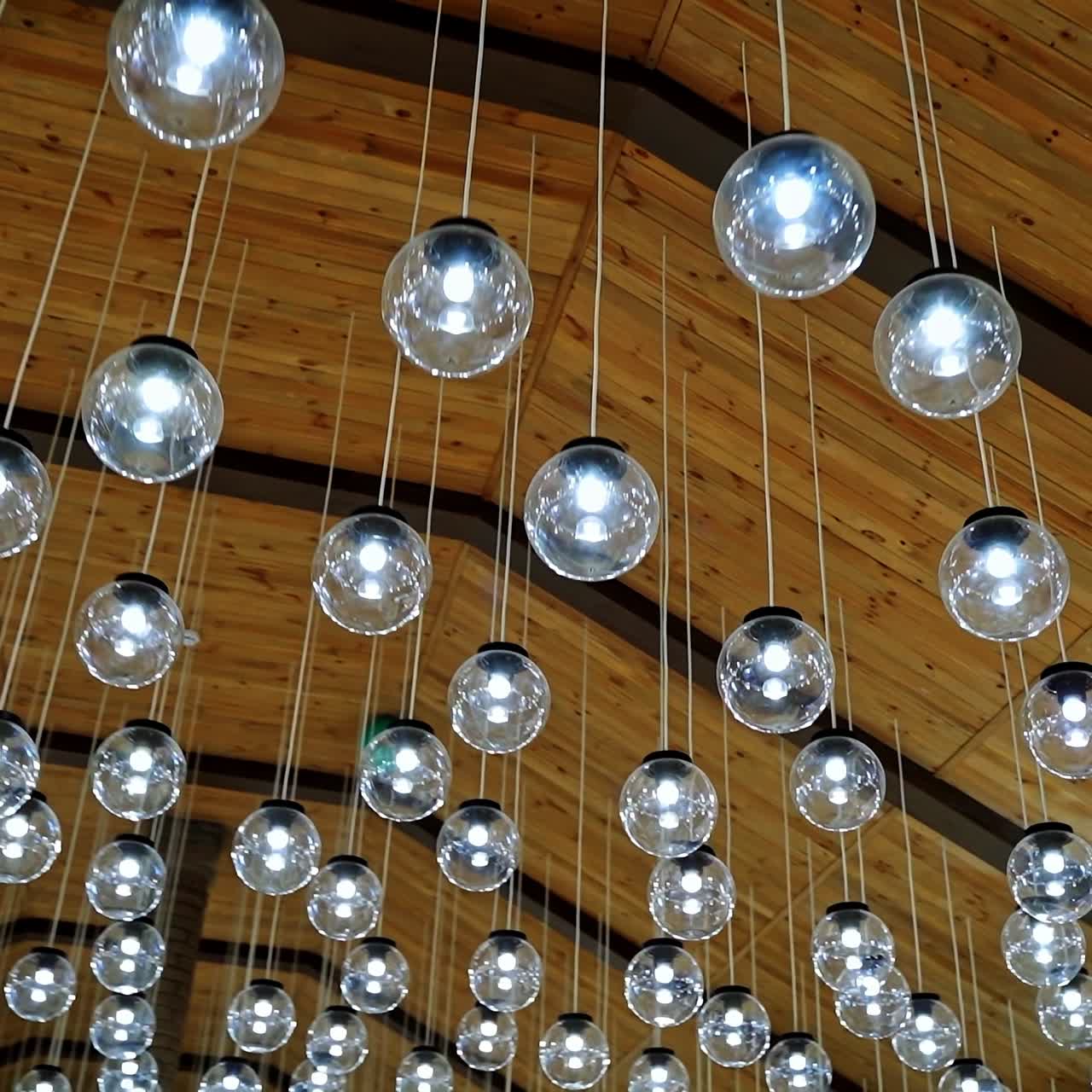 Luxury interior of glass light bulbs. Futuristic pendant lights of round shape. Many shiny balls on the ceiling background.