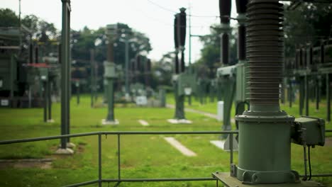 Dos-Ingenieros-Inspeccionan-Equipos-En-Una-Subestación-Eléctrica,-Se-Centran-Superficialmente-En-Primer-Plano.