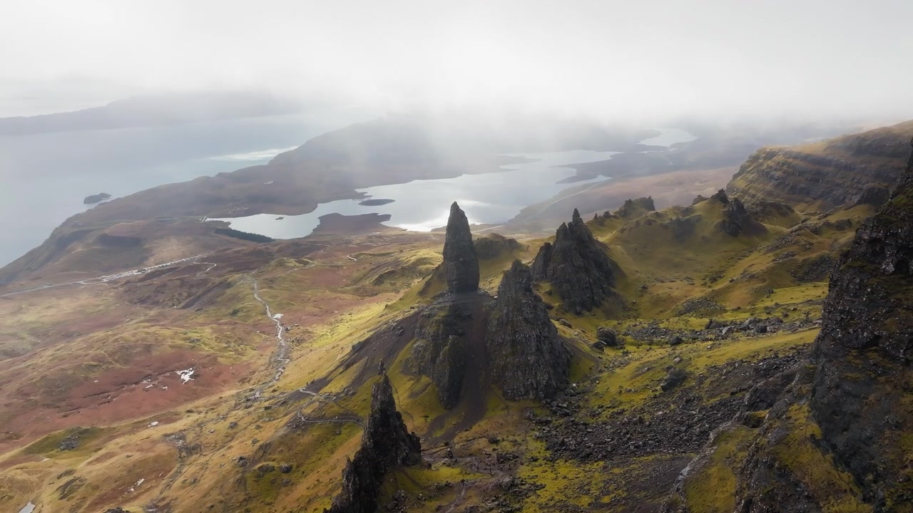 Pomalý filmový přelet dronu nad skalním útvarem Storr, ostrov Skye, Skotsko, s hustou oblačností nad hlavou, mlha se hromadí v údolí a stoupá po útesu
