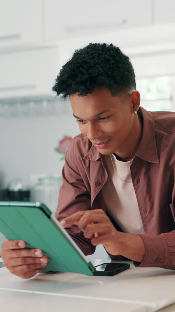 Young Man Smiling While Using Digital Tablet at Home