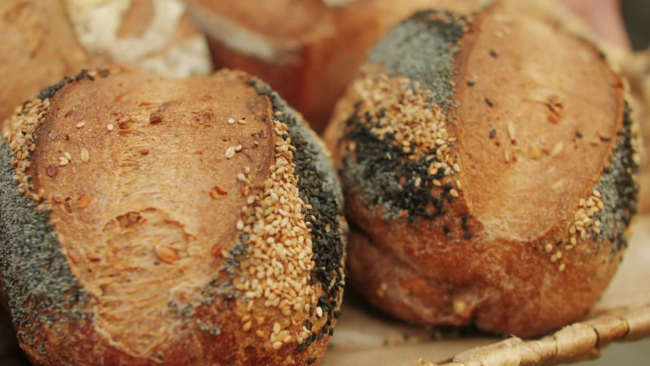 The baker holds in hands a of fresh bread with black poppy garnish on top close-up. Artisan bread is making by skill bakers using natural and high-quality ingredients. Food with health and flavour benefits.