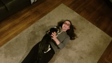 young woman plays with large cat on livingroom rug before it walks away