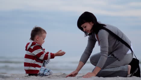 mother and boy play with sand. active parents, outdoor activity on summer vacations with children