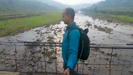 young-traveler-man-walking-on-iron-suspension-bridge-at-morning