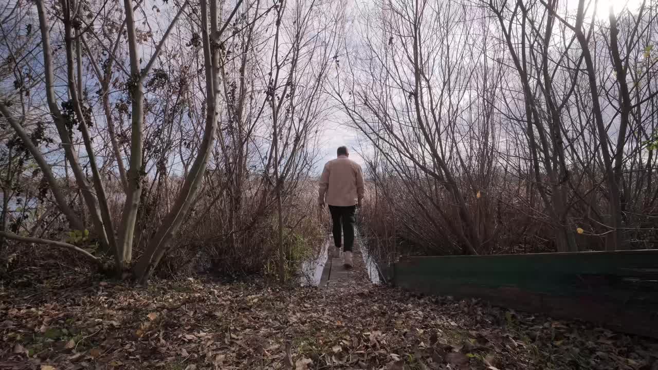Man walks on wooden pier in a autumn day