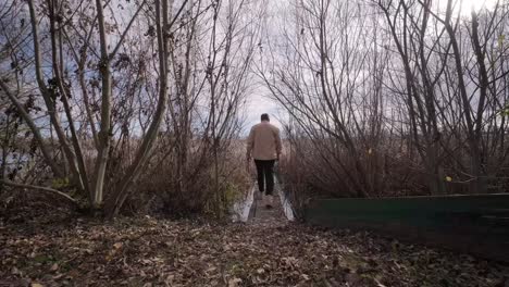 man walks on wooden pier in a autumn day