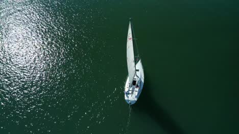 Ein-Segelboot-In-Der-Sonne,-Während-Der-Jachthafen-Langsam-Glitzert