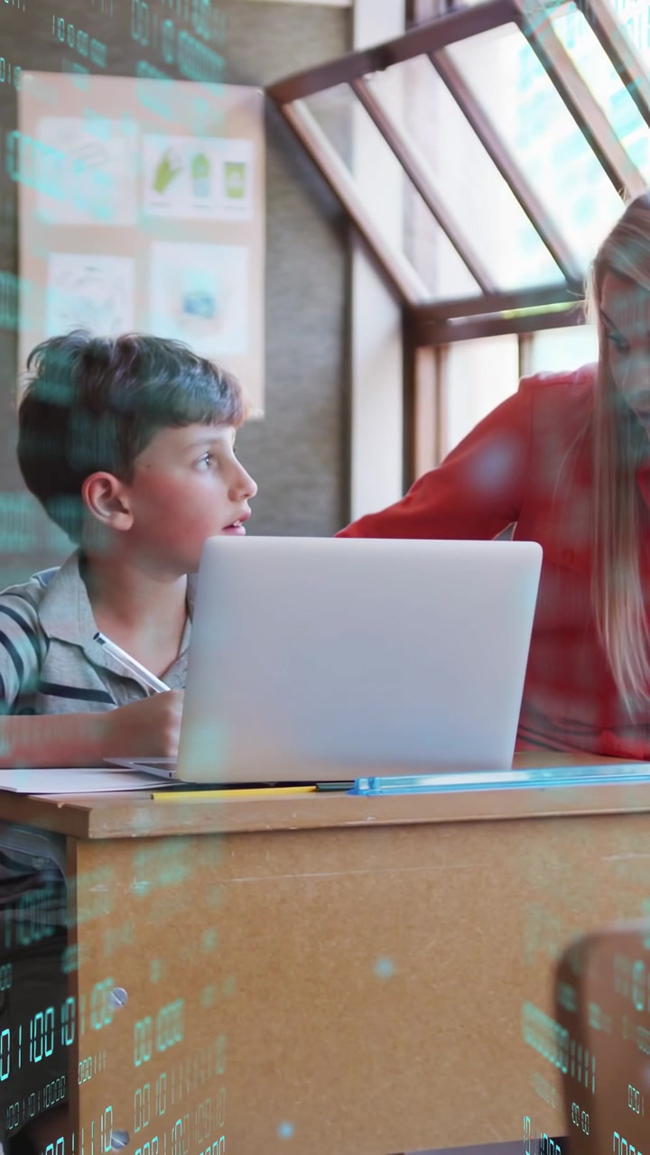 Vertical video: Child asking, teacher leaning in and guiding on laptop and paper for learning