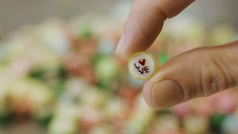 hand holding caramel candy with love on it. candies in the background