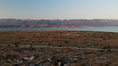 Sunset-and-empty-road,-an-aerial-view-on-the-sea-and-the-mountain