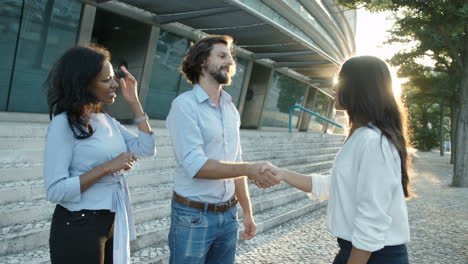 director and job applicant shaking hands at end of successful meeting with business colleague next to them