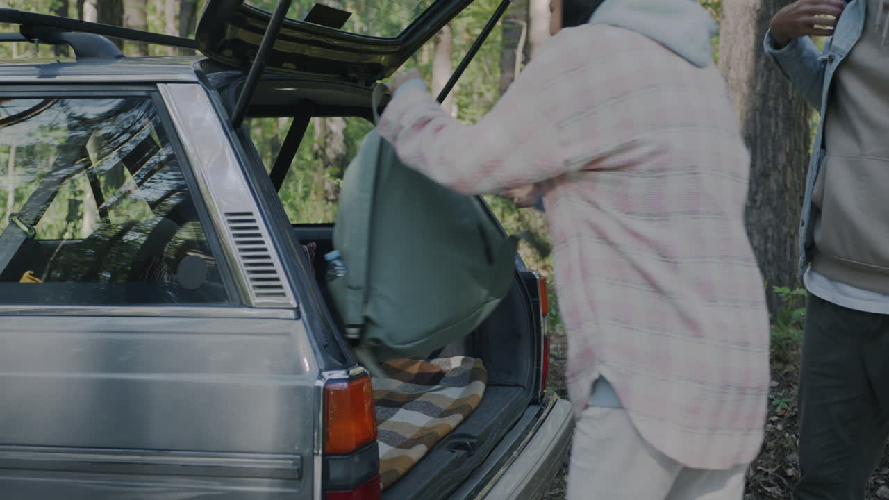 People Loading a Car Trunk in the Forest