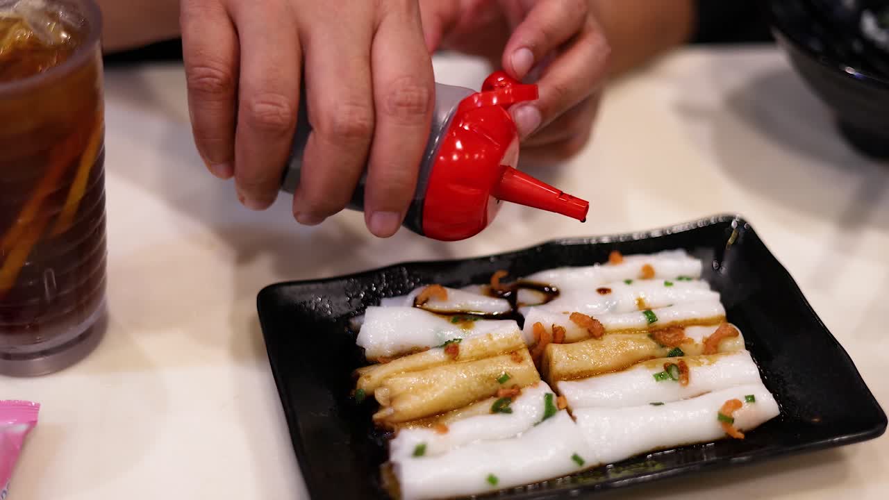 Sauce being poured over rice noodle rolls
