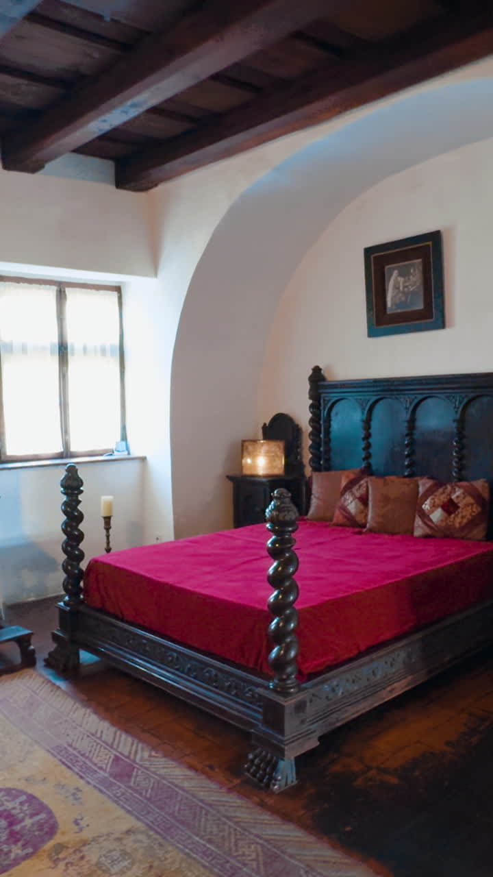 Interior of the medieval Bran castle in Brasov, Romania. Approaching big wooden bed with red cover on. Vertical video